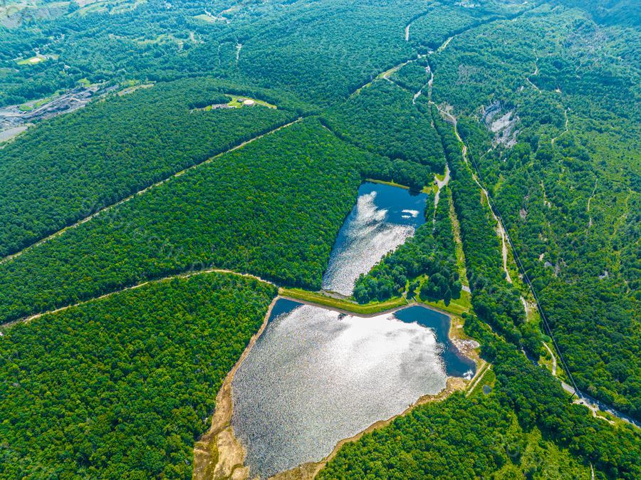 Aerial view of two lakes surrounded by dense green forest with winding rivers at afternoon light.